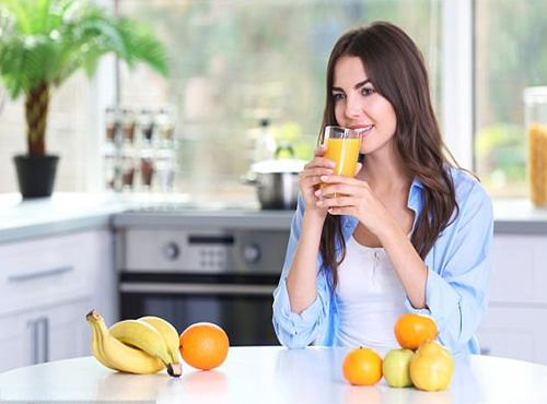 Lady drinking orange juice promoting special discounts on natural supplements