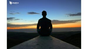 A man watching the sunset from a mountain top, embracing the essence of health for wellness through connection with nature