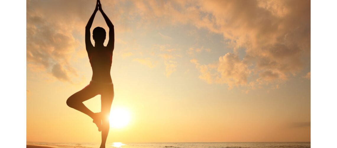 A woman practicing yoga on a beach at sunset, symbolizing the harmony of body and mind."