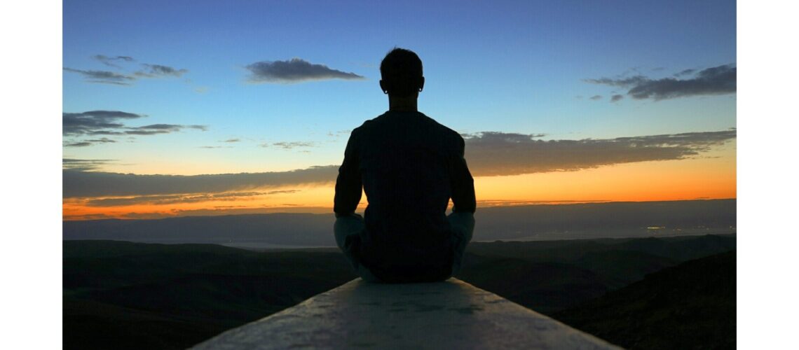 A man watching the sunset from a mountain top, embracing the essence of health for wellness through connection with nature